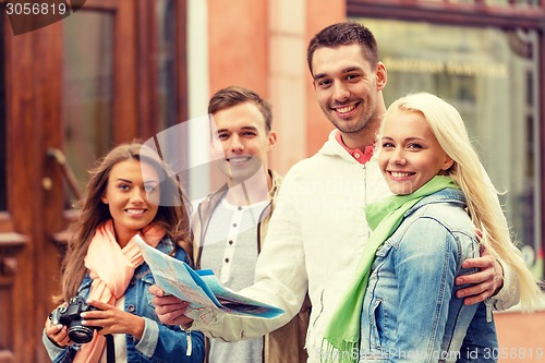 Image of group of smiling friends with map and photocamera