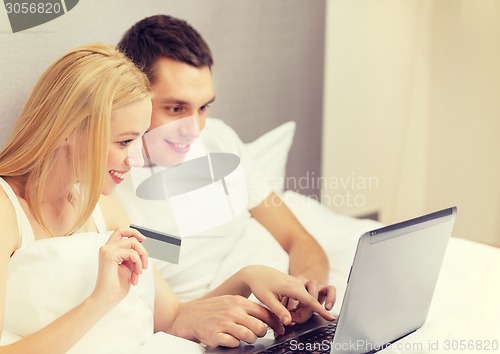 Image of couple in bed with laptop computer and credit card