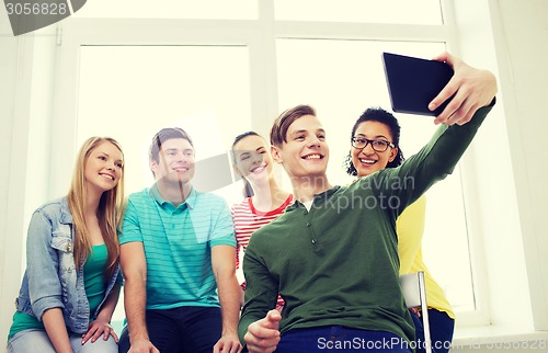 Image of smiling students making picture with tablet pc