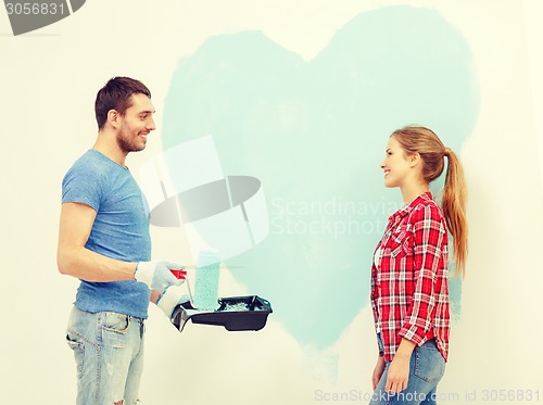 Image of smiling couple painting big heart on wall