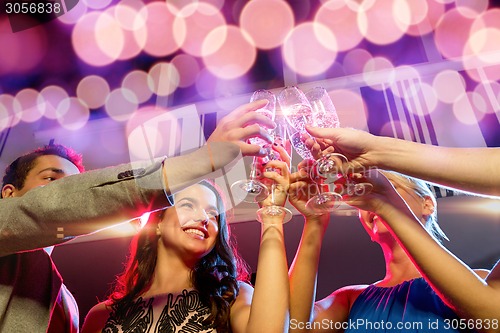 Image of smiling friends with glasses of champagne in club