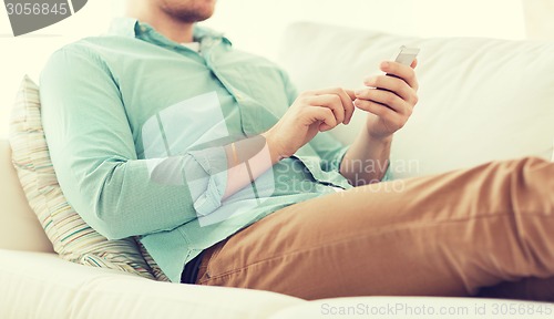 Image of close up of man sitting with smartphone at home