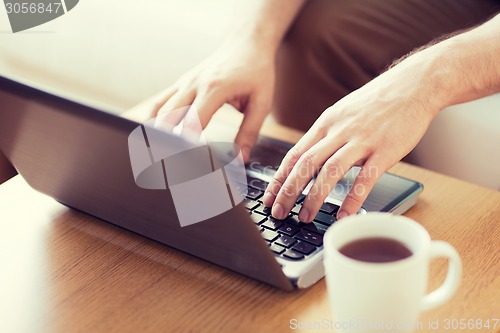 Image of close up of man with laptop and cup at home