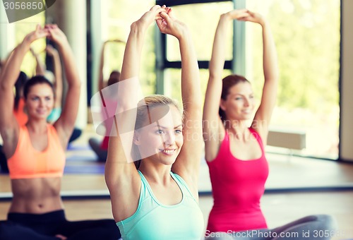 Image of group of smiling women stretching in gym