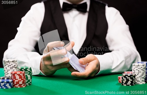 Image of holdem dealer with playing cards and casino chips