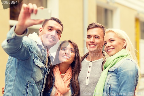Image of group of smiling friends making selfie outdoors