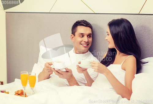 Image of smiling couple having breakfast in bed in hotel