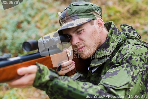 Image of young soldier or hunter with gun in forest