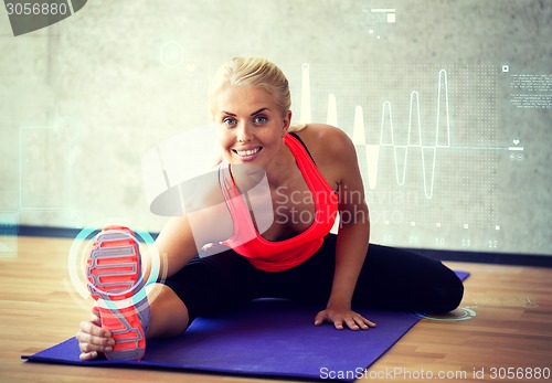 Image of smiling woman doing exercises on mat in gym