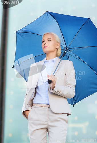 Image of young serious businesswoman with umbrella outdoors