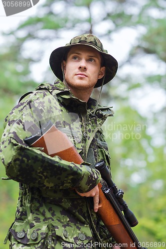 Image of young soldier or hunter with gun in forest