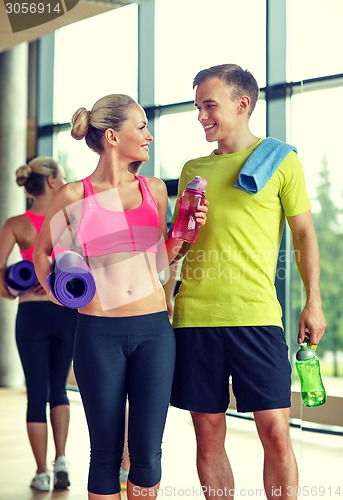 Image of smiling couple with water bottles in gym