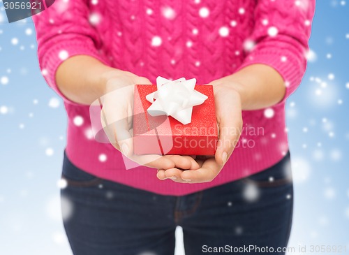 Image of close up of woman in pink sweater holding gift box