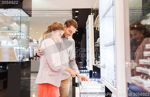 Image of happy couple choosing engagement ring in mall