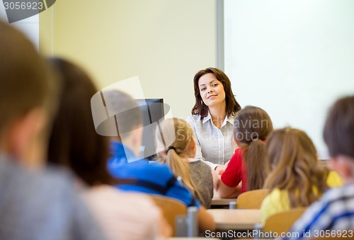 Image of group of school kids raising hands in classroom