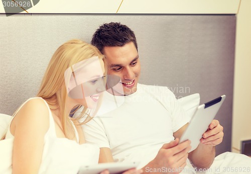 Image of smiling couple in bed with tablet pc computers