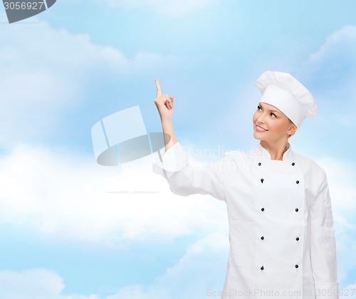 Image of smiling female chef pointing finger to something