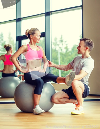 Image of smiling man and woman with exercise ball in gym