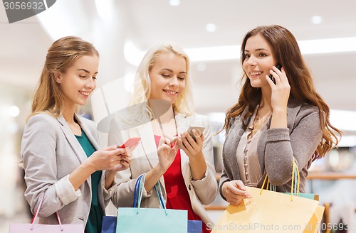 Image of happy women with smartphones and shopping bags