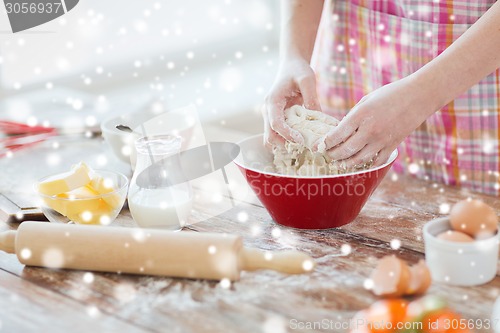 Image of close up of female hands kneading dough at home