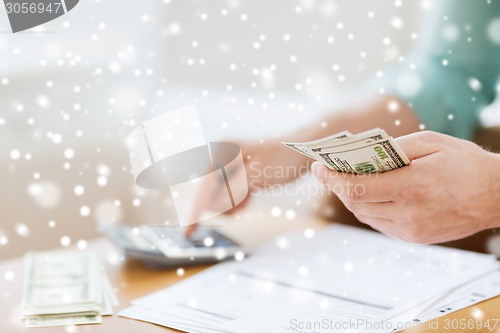 Image of close up of man counting money and making notes