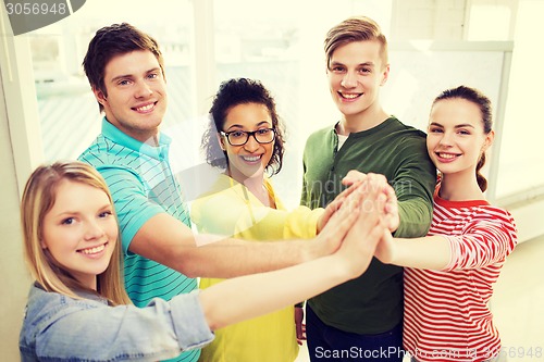 Image of five smiling students giving high five at school