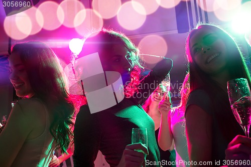 Image of smiling friends with glasses of champagne in club