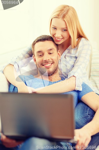 Image of smiling happy couple with laptop at home