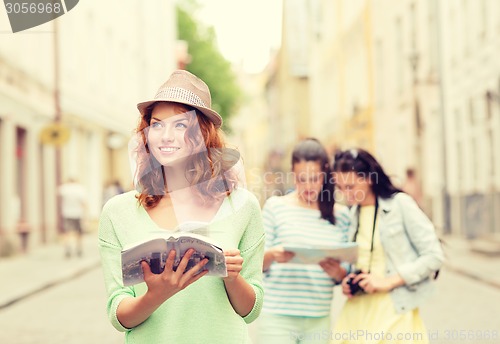 Image of smiling teenage girls with city guides and camera