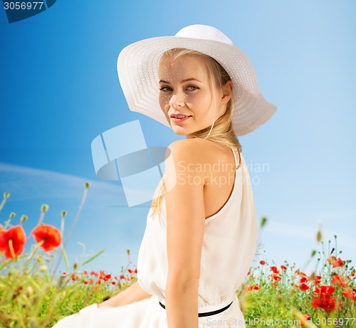 Image of smiling young woman in straw hat on poppy field