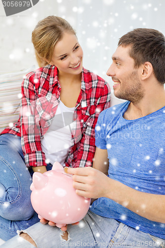 Image of smiling couple with piggybank sitting on sofa