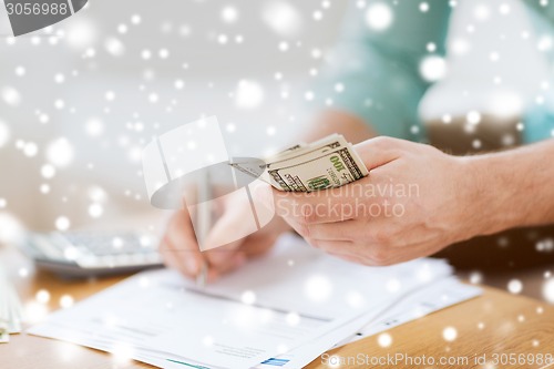 Image of close up of man counting money and making notes