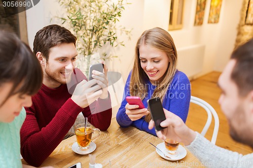 Image of group of friends with smartphones meeting at cafe