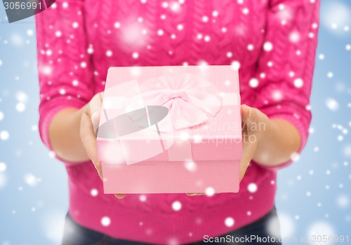 Image of close up of woman in pink sweater holding gift box