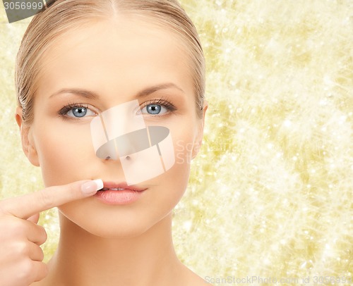 Image of beautiful young woman pointing finger to her lips