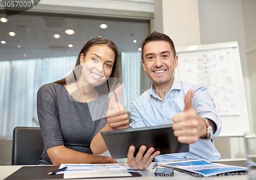 Image of smiling businesspeople with tablet pc in office