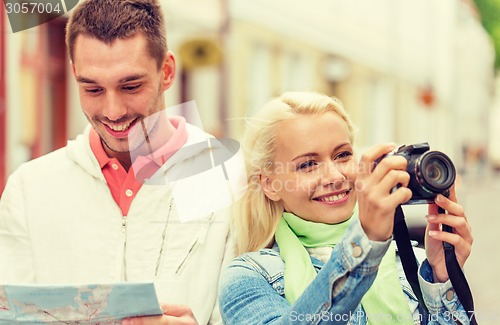Image of smiling couple with map and photocamera in city