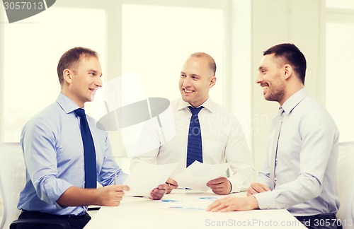 Image of smiling businessmen with papers in office