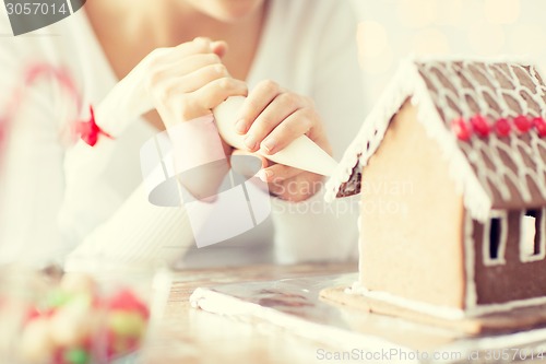 Image of close up of woman making gingerbread house at home