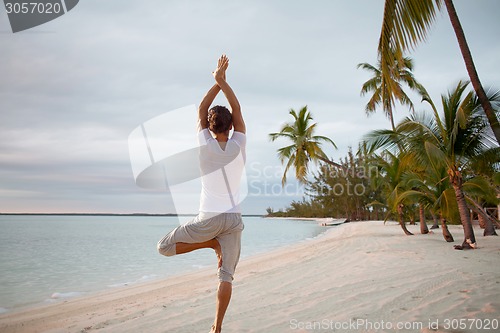 Image of young man making yoga exercises outdoors