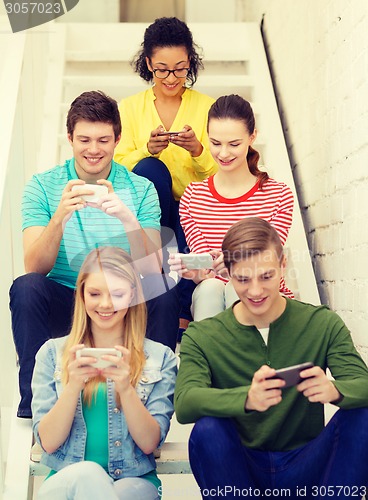 Image of smiling students with smartphone texting at school