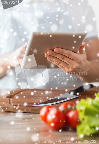 Image of closeup of man reading recipe from tablet pc