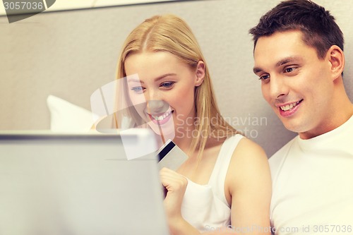 Image of couple in bed with laptop computer and credit card