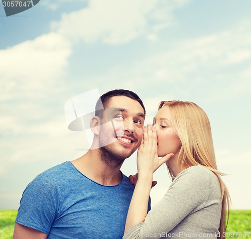 Image of smiling girlfriend telling boyfriend secret