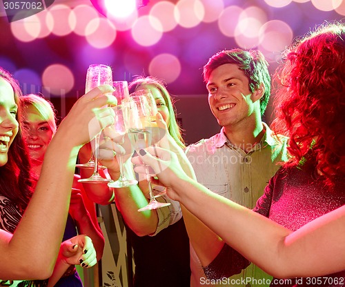 Image of smiling friends with glasses of champagne in club