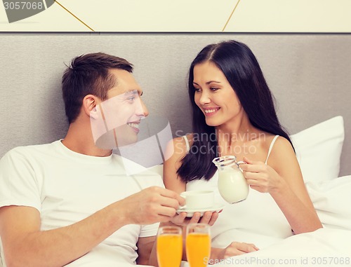 Image of smiling couple having breakfast in bed in hotel