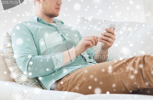 Image of close up of man sitting with smartphone at home