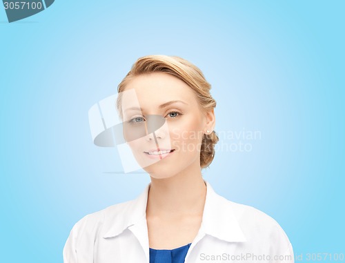 Image of smiling young female doctor over blue background