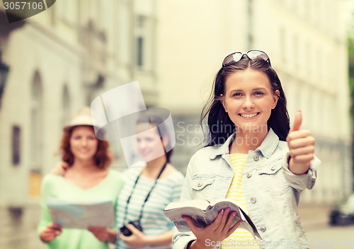 Image of smiling teenage girls with city guide and camera