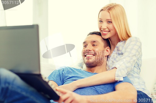 Image of smiling happy couple with laptop at home